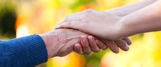 Close-up image of an elderly hand being held by a younger-looking hand